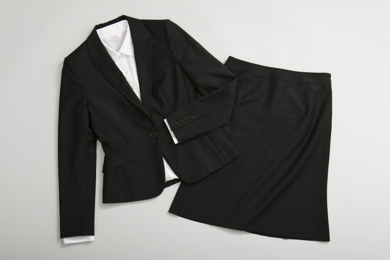 黒のジャケット、白のブラウス、黒のスカートの写真