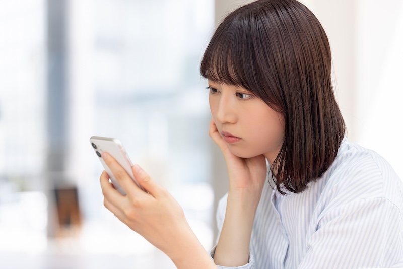 スマートフォンを見て考える女性