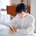ノートに書きものをする女性