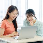 パソコンを見ながら話す学生たち