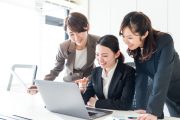 オフィスでパソコンを見ながら談笑する３人のイメージ