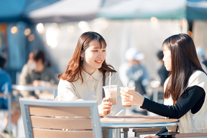 テラス席でコーヒーを飲む2人の学生