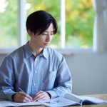 家のリビングで勉強する学生